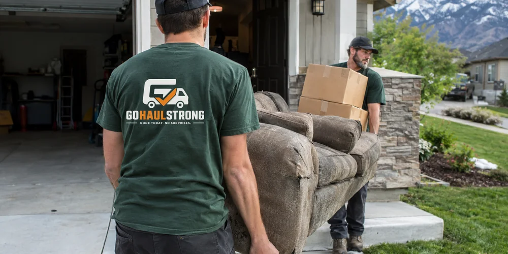 GoHaulStrong crew carrying a couch and boxes out of a Utah home during a residential junk removal